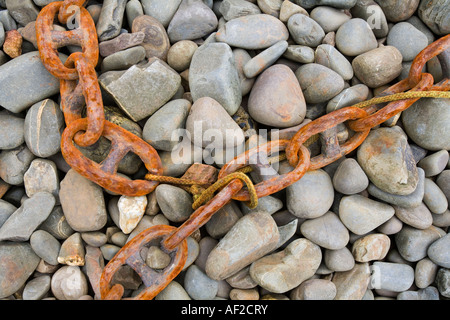 Rusty old anchor chain on a pebble beach United Kingdom Stock Photo
