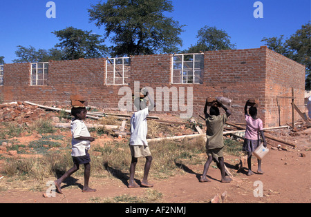 Zimbabwe Mola near Kariba Boys and girls carrying bricks for building school Stock Photo