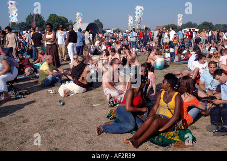 Large multiracial crowd of young people sitting and enjoying Burgess Park in South London. Stock Photo