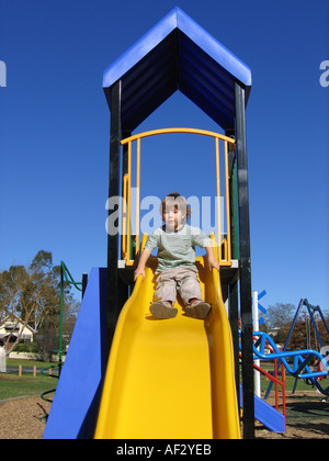 Young boy going down a slide in a park Stock Photo