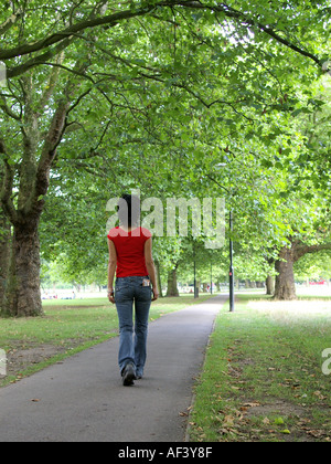 dark haired woman walking alone in park in jeans in Clapham London with visible tobacco pouch in back pocket. Stock Photo
