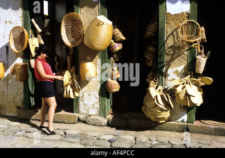Girl at shop on old cobbled street selling baskets and woven goods in Parati on the Costa Verde Rio de Janeiro State Brazil Stock Photo