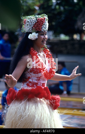 Side half length portrait of lovely local dark skinned Tahitian girl dancer swinging her hips in grass skirt with arms out Stock Photo