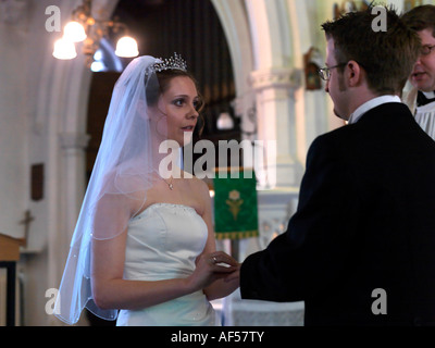 Bride putting Ring on Grooms Hand During the Wedding Ceremony Surrey England Stock Photo