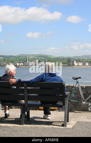 two cyclists taking a break in Omeath, County Louth, Ireland - looking across Carlingford Lough to Warrenpoint Stock Photo