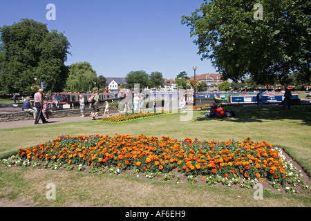 People walking along towpath in Bancroft Gardens with narrow boats and canal basin behind Stratford upon Avon UK Stock Photo