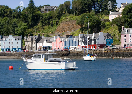 Motor launch in Tobermory harbour with colourful houses along quayside Isle of Mull Scotland UK Stock Photo
