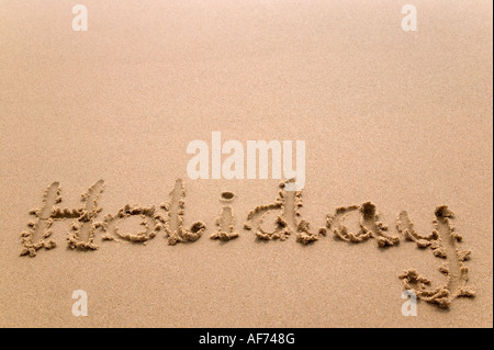 Holiday handwritten in golden sand plenty of copy space Stock Photo