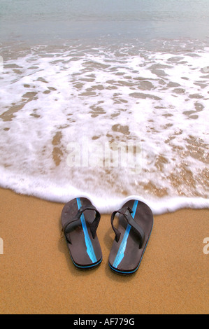 Pair of flip flops at the beach about to be washed away by the tide Stock Photo
