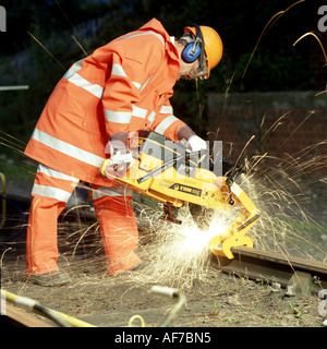 Nighttime close-up of railway worker cutting track section. Stock Photo