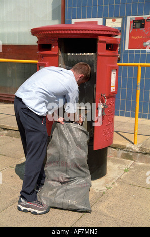 postman collecting post from red pillar postbox Stock Photo