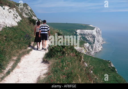 Couple walking along chalky path above the White Cliffs of Dover and Langdon Bay, Kent, England Stock Photo