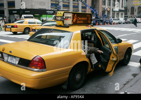 white caucasian passenger closes rear door of yellow cab on taxi rank at crosswalk on 7th Avenue outside Madison Square Garden Stock Photo
