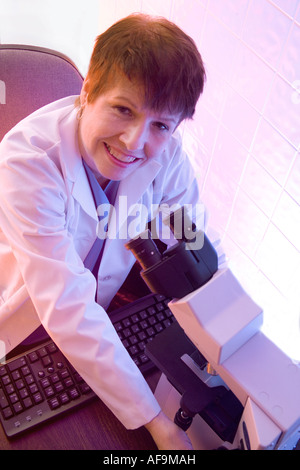 Female researcher using microscope. Stock Photo