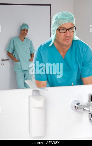 Surgeon washing his hands, female surgeon in background Stock Photo