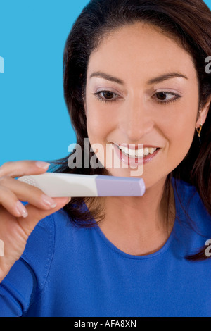 Hispanic woman happy to read results of a home pregnancy test. Stock Photo