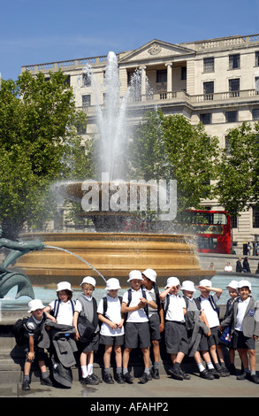 Children posing for photo by the fountain  in Trafalgar Square, London, England. UK, 2006. Stock Photo