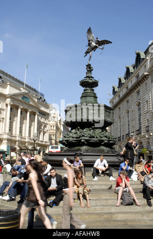Tourists sitting on the steps around the  Bronze Statue Of  Eros, Piccadilly Circus, London, England. Monument erected 1893 Stock Photo