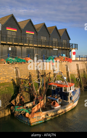Sunrise in a fishing harbour with buildings and trawler Stock Photo