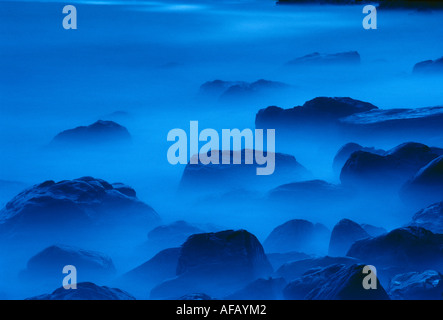 abstract detail of waves breaking around rocks at twilight Caerfai Pembrokeshire Wales UK Stock Photo