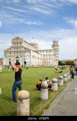 Tourist posing for photo of himself holding up the Leaning tower in Campo di Miracoli field of Miracles Pisa Tuscany Italy Stock Photo