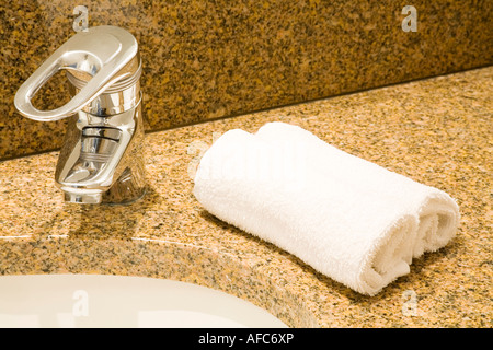 Closeup of a luxurious bathroom sink with fluffy face towels on a granite counter Stock Photo