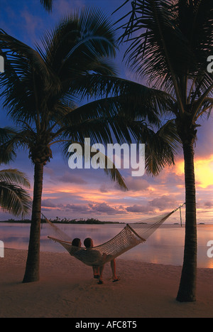 Couple relaxing in a hammock at sunset, Aitutaki Lagoon Resort, Cook Islands, South Pacific Stock Photo