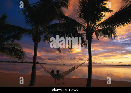 Couple relaxing in a hammock at sunset, Aitutaki Lagoon Resort, Cook Islands, South Pacific Stock Photo