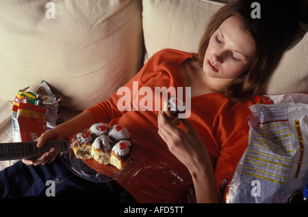 woman binge eating infront of the television Stock Photo