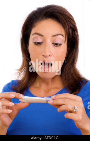 Hispanic woman surprized with the results of a home pregnancy test. Stock Photo