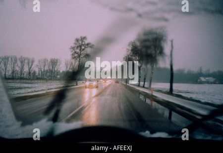 snowy winter road seen through car windshield RHD Stock Photo