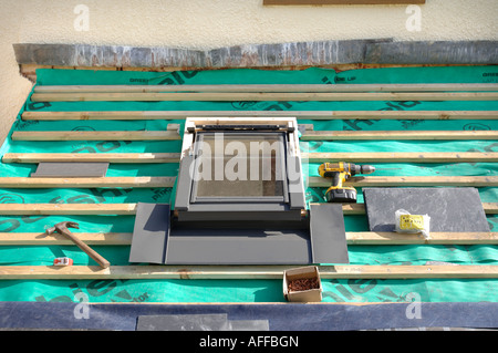 FITTING A VELUX WINDOW ON A SLATE ROOF UNDER CONSTRUCTION SHOWING THE BREATHABLE ROOFING FELT WITH WOODEN BATONS Stock Photo
