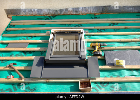FITTING A VELUX WINDOW ON A SLATE ROOF UNDER CONSTRUCTION SHOWING THE BREATHABLE ROOFING FELT WITH WOODEN BATONS Stock Photo