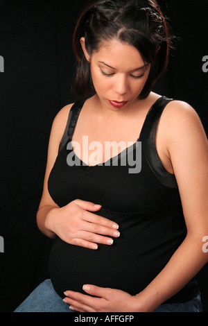 A  pregnant woman pretty maternity pregnancy on dark background front view alone single one photography photo vertical in USA hi-res Stock Photo