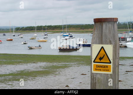 Sign on wooden post warning of danger due to strong current. Itchenor harbour, West Sussex Stock Photo