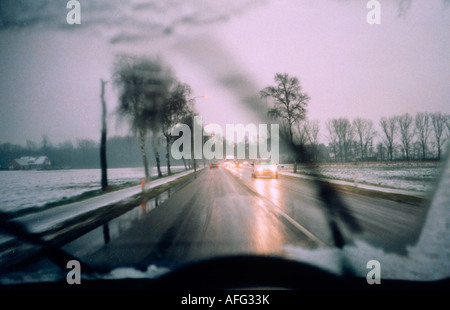 snowy winter road seen through car windshield LHD Stock Photo