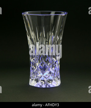 A crystal vase on black paper with a coloured light shining from beneath and highlighting the cut pattern shot in the studio Stock Photo