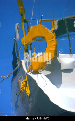 A lifebuoy and yacht reflected in the blue water. Picture by Jim Holden Stock Photo
