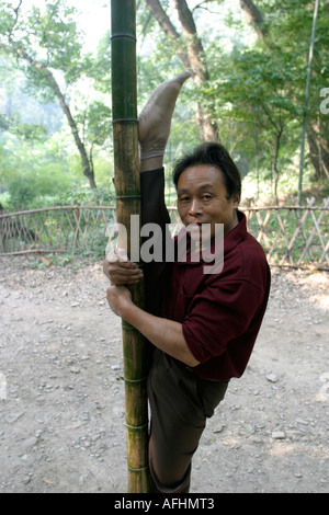 A man doing streaching exercises in Hangzhou's vast West Lake park raises one leg above his head while standing on the other leg. Stock Photo