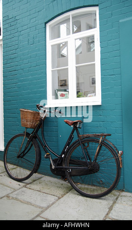 An Old Bike Leaning Against A Blue Painted Brick Wall Stock Photo