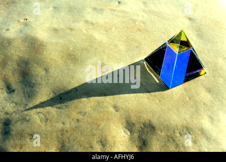 Glass pyramid prism light colour beach sand rock pebble sea seashore coast Stock Photo