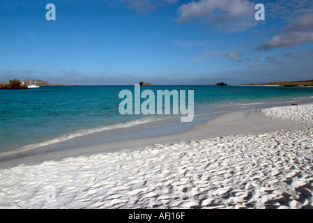 Waves lapping on secluded beach of Galapagos Islands Ecuador South America with tour boat on horizon Stock Photo