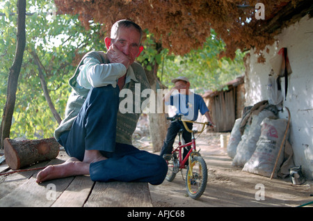 older man sitting on his porch with grandson in background small village in south Western Turkey. Stock Photo