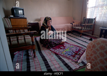 Turkish Islamic woman praying in her front room at home in town of Mulga in the Southwest of Turkey. Stock Photo