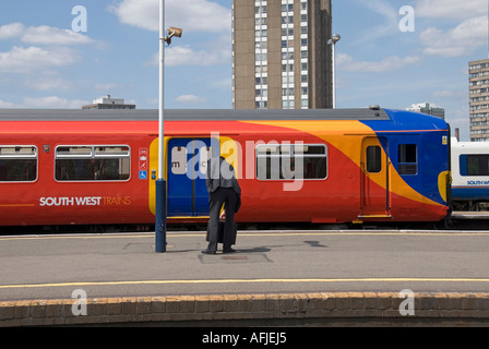 Clapham Junction railway station with gentleman wearing formal business suit waiting on platform as South West Train arrives South London England UK Stock Photo