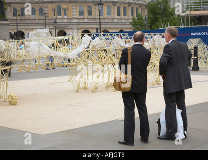 Two men in suits discuss one of Theo Jansen s Stranbeest in Trafalgar Square Stock Photo