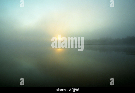 Rising sun on the misty lake Stock Photo