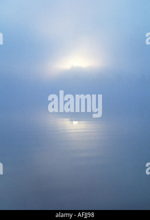 Rising sun on the lake in misty morning Stock Photo