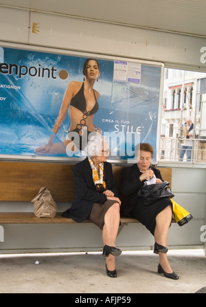 Editorial use only No model release two elderly italian women in black business dress seated in a Vaporetto stop young bikini Stock Photo