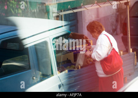 Editorial use only No model release old Italian woman selecting fruit from the back of a produce truck Stock Photo